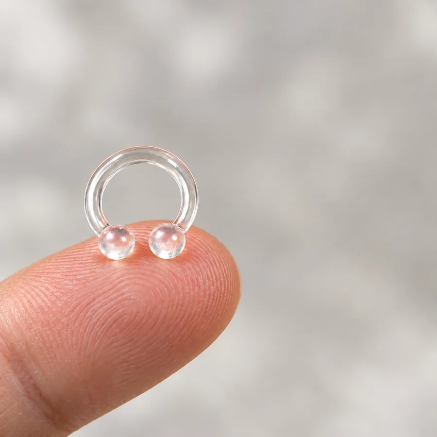 The clear NASMA ring resting on a fingertip